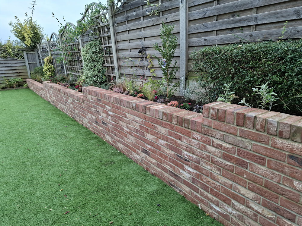 After New brick retaining wall including raised bed